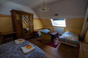 A room with two beds, a wooden wardrobe, a desk, and a chair.
