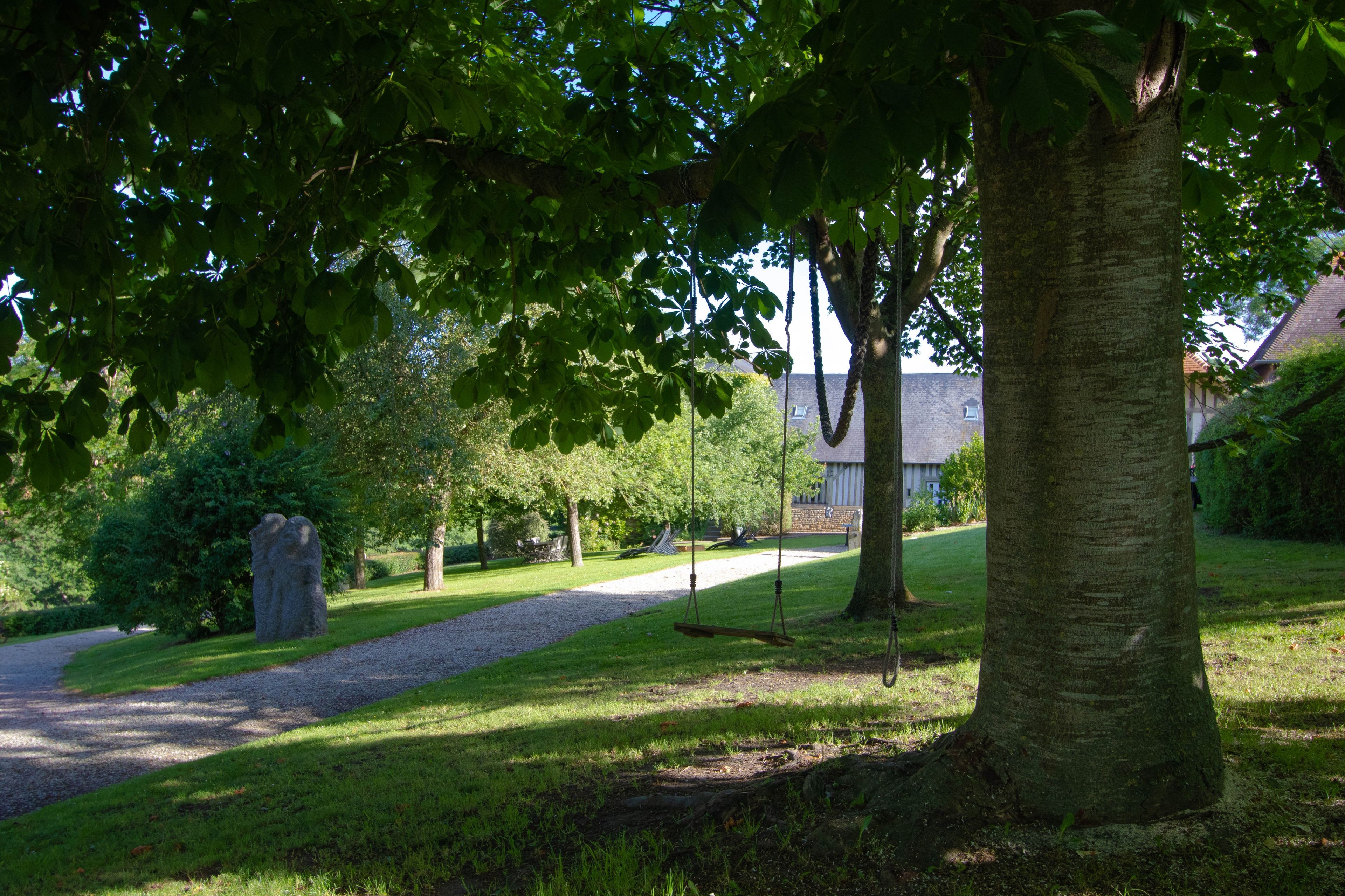 A park with a gravel path, trees, and a stone monument.