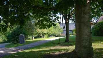 A park with a gravel path, trees, and a stone monument.