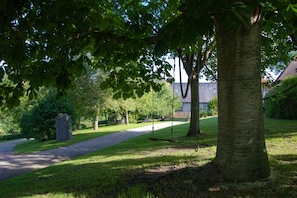 En park med en grusgång, träd och ett stenmonument.
