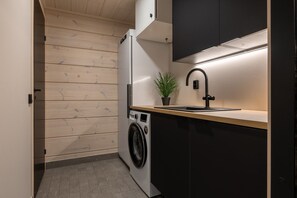 A compact kitchen with a washing machine, a sink, and a potted plant. - Yläkasi C by Holiday in Lapland (Levi)