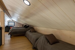 A loft bedroom with two beds, wooden slats on the ceiling, and a window. - Yläkasi C by Holiday in Lapland (Levi)