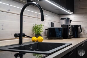 Een moderne keuken met een zwarte spoelbak, een broodrooster, een koffiezetapparaat en een plant in pot.