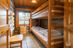 A cabin interior with a wooden desk, bunk beds, a window, and a lamp.