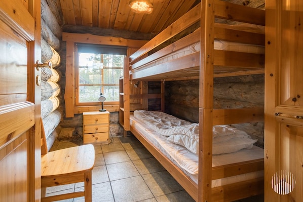 A cabin interior with a wooden desk, bunk beds, a window, and a lamp.