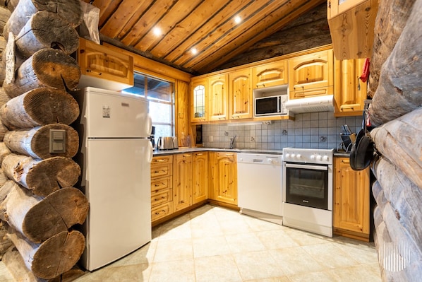 A log cabin interior with wooden cabinets, a refrigerator, a microwave, a stove, and a dishwasher.