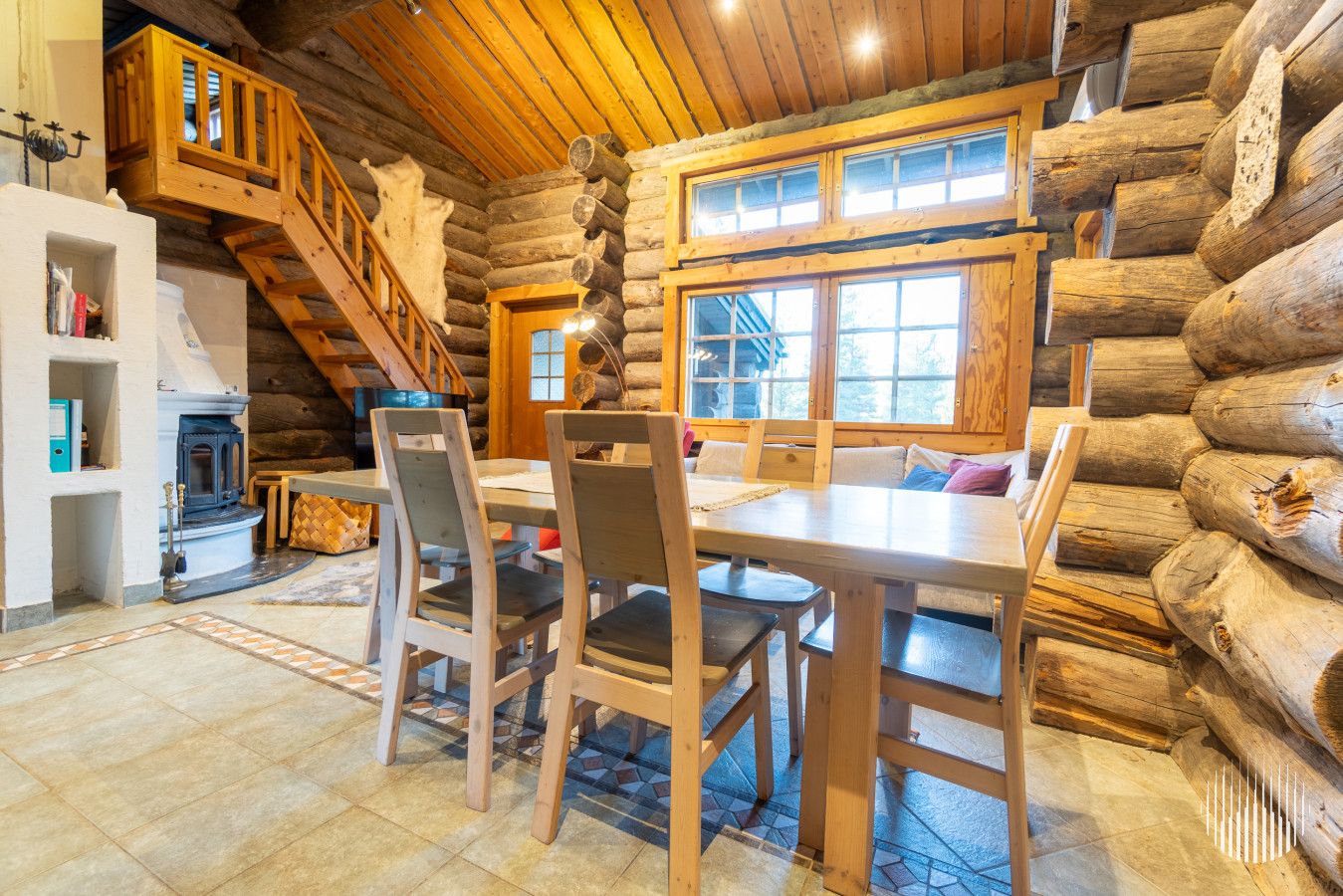 L’intérieur d’une cabane en rondins comprend un coin repas, un escalier en bois et une cheminée.