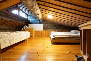 A small attic bedroom with two beds, wooden flooring, and a sloped ceiling.
