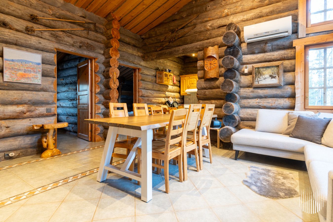 L’intérieur d’une cabane en rondins comprend un coin repas, un canapé et une cheminée.