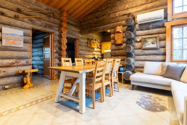 A log cabin interior with a dining area, a sofa, and a fireplace.
