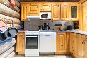 A log cabin kitchen with wooden cabinets, a white stove, a dishwasher, and a microwave.
