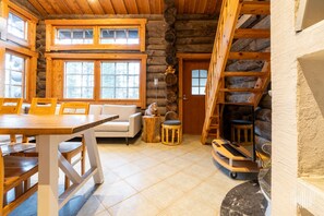 A log cabin interior with a dining area, sofa, and a staircase.