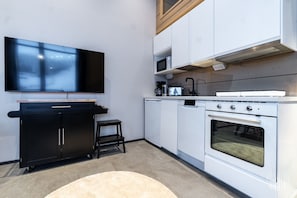 A compact kitchen with a built-in oven, microwave, and a flat-screen TV mounted on the wall. - Levi West Slope 1 by Holiday in Lapland (Levi)