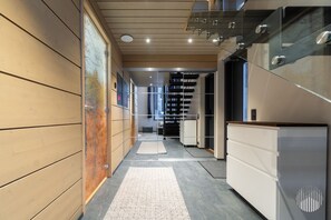 A modern hallway with a wooden wall, a glass staircase, and a white reception desk. - Levi West Slope 4 by Holiday in Lapland (Levi)