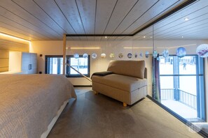 A bedroom with a bed, a chair, a wardrobe, and a large window. - Levi West Slope 4 by Holiday in Lapland (Levi)