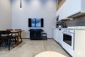Eine kompakte Küche mit Essbereich, einem Wand-Fernseher und einem Einbauofen.