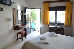 A hotel room with a bed, a desk, a chair, a television, and a window with curtains. - Holiday Apartment in Paleochora With a Balcony (Kantanos-Selino)