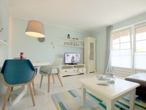 Ett modernt vardagsrum med tv, matplats och soffa.