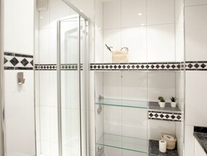 A modern bathroom with a glass shower enclosure, white tiles, and a decorative black and white border. - Holiday Apartment With 1 Bedroom (Wyk auf Foehr)