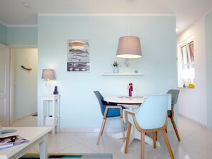 A dining area with a table, chairs, and a wall-mounted lamp. - Holiday Apartment With 1 Bedroom (Wyk auf Foehr)