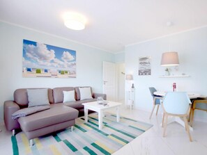 Ett modernt vardagsrum med en soffa, ett soffbord och en matplats med en stol och ett bord.