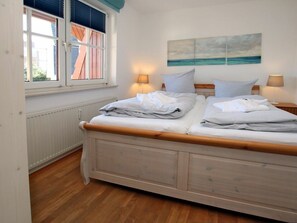 A bedroom with a double bed, two bedside lamps, a window with blinds, and a painting on the wall. - Holiday Apartment With 1 Bedroom (Wyk auf Foehr)