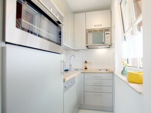 Ett kompakt kök med en inbyggd ugn, mikrovågsugn och en diskho.