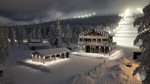 A multi-story lodge with a balcony, surrounded by snow-covered trees and a mountain backdrop. - Levi West Peak View by Holiday in Lapland (Levi)