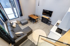 A modern living space with a sofa, a dining table, a TV, and a kitchen area. - Levi West Slope 3 by Holiday in Lapland (Levi)