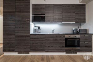 Een moderne keuken met donker houten kasten, een ingebouwde magnetron, een koffieapparaat, een broodrooster en een oven.
