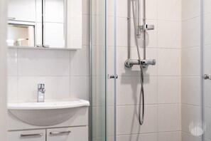 A modern bathroom with a white sink, a glass shower enclosure, and a mirror above the sink. - Sivulantie 4 207 by Holiday in Lapland (Äkäslompolo)