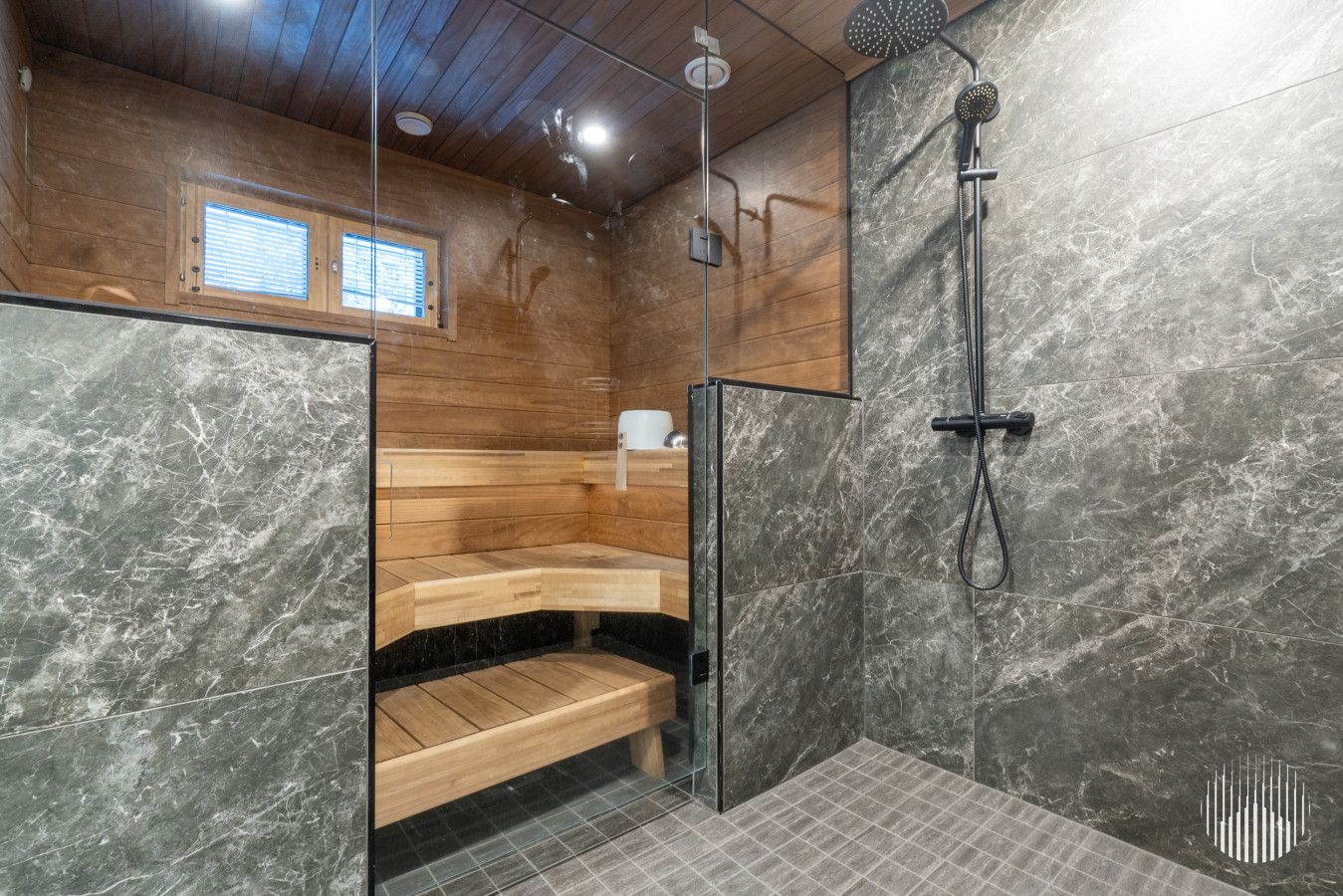 A modern bathroom with a wooden bench, a glass shower enclosure, and a marble wall.