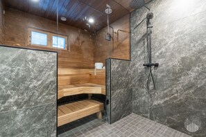 A modern bathroom with a wooden bench, a glass shower enclosure, and a marble wall.