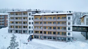 A multi-story hotel with balconies, a covered outdoor area, and a snow-covered landscape.