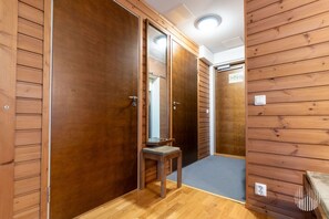 A hallway with wooden walls and doors, a small bench, and a light switch on the wall.