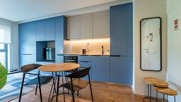 A modern kitchen with blue cabinets, a round wooden table, and black chairs.
