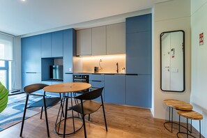 Una cocina moderna con armarios azules, una mesa redonda de madera y sillas negras.