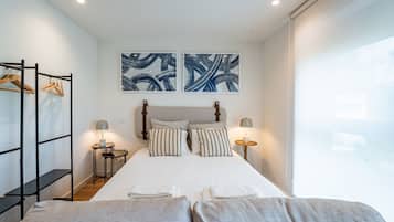 Quarto moderno com cama, duas mesas de cabeceira, um guarda-roupa e arte abstrata na parede.