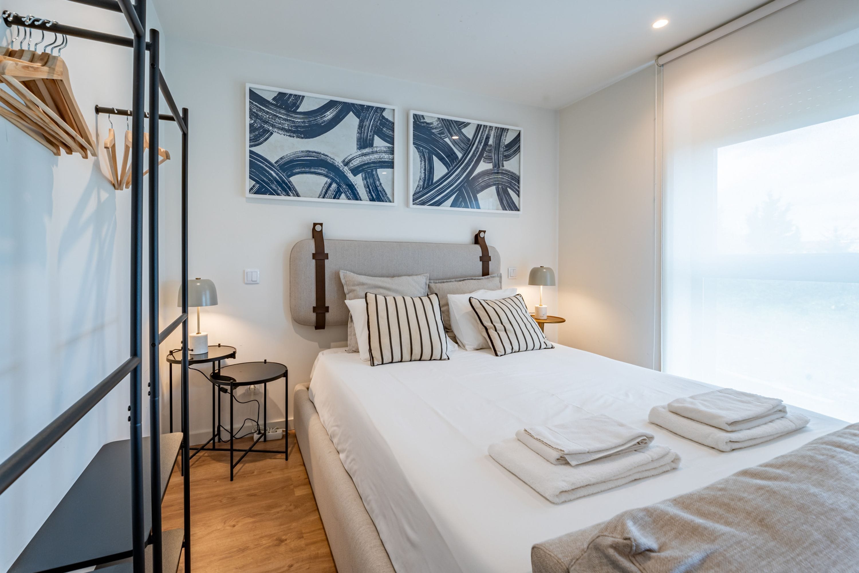 Ein Hotelzimmer mit einem Bett, Nachttischen, einer Lampe und Kunstwerken an der Wand.