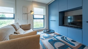 Ein modernes Wohnzimmer mit einer Couch, einem Couchtisch und einem Flachbildfernseher, der an einer blauen Wand angebracht ist.