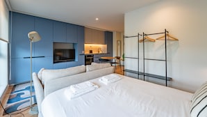 Ein modernes Hotelzimmer mit einem Bett, einem Fernseher, einem Schreibtisch und einer Küchenzeile.