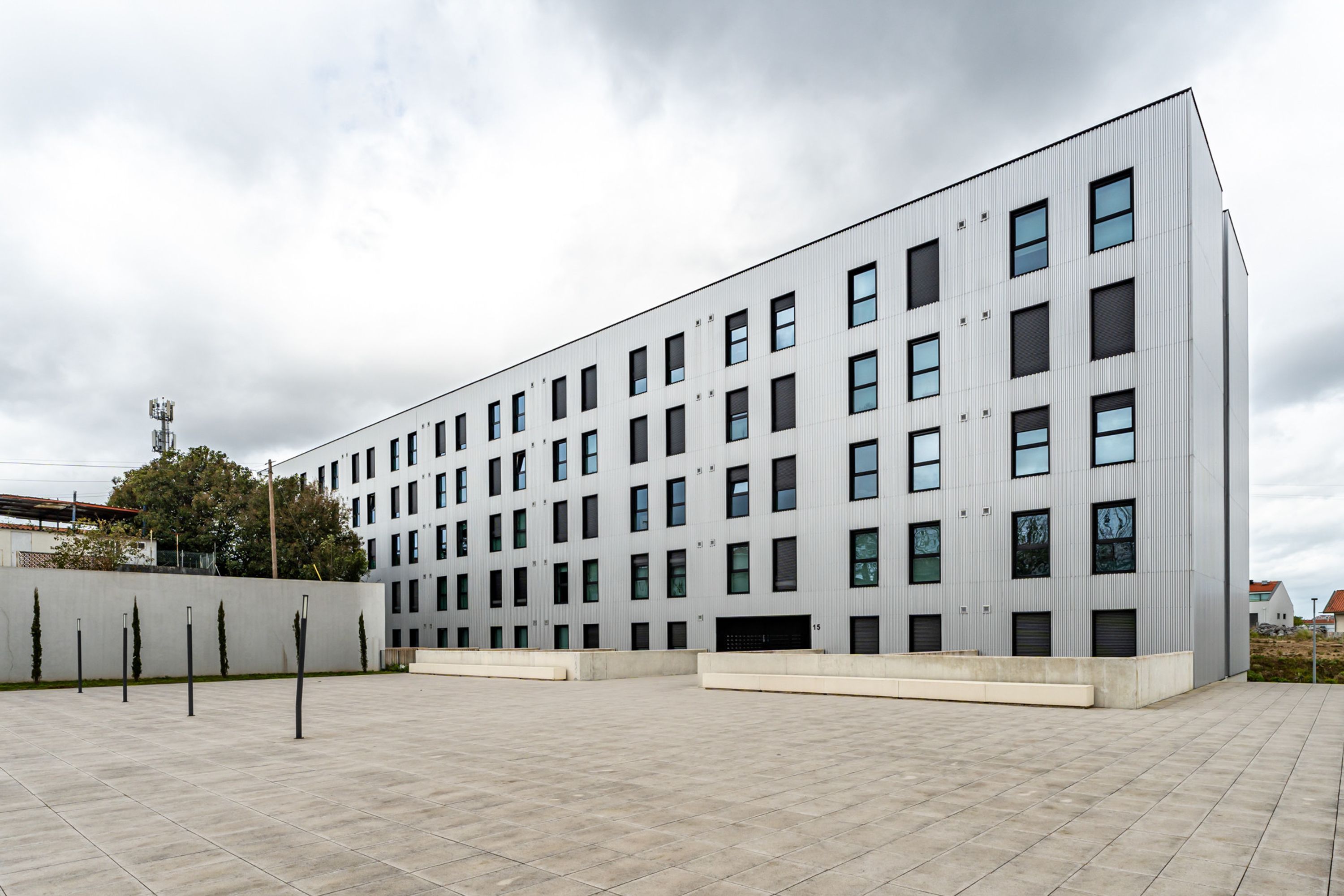 Ein modernes Gebäude mit flachem Dach, zahlreichen Fenstern und einem gepflasterten Innenhof.
