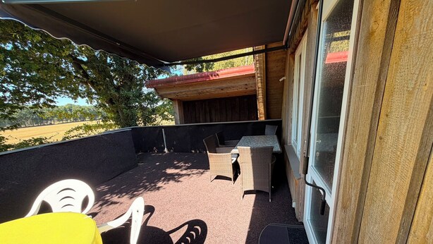 An outdoor patio with a covered seating area, a table, and chairs. - Feldblick Rastede Vacation Rental – Covered Patio, Air Conditioning, Dogs Welcome (Rastede)