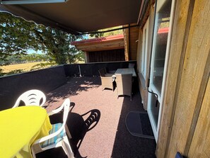 An outdoor patio with a covered seating area, a table, and chairs.