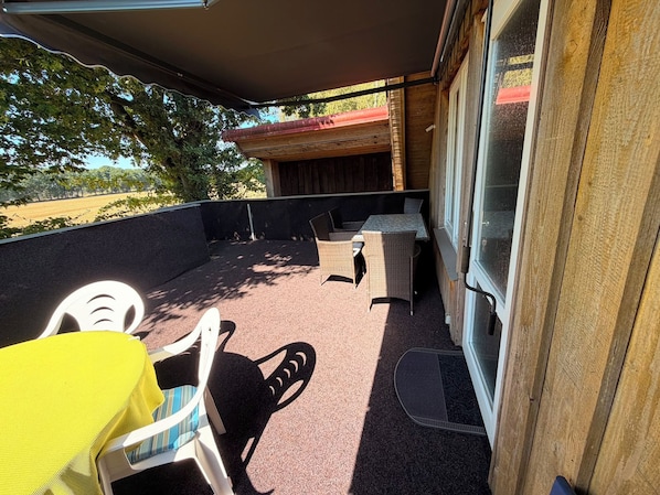 Une terrasse extérieure dotée d’un espace salon abrité, d’une table et de chaises.