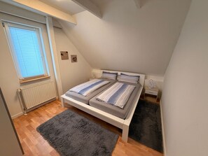 A bedroom with a bed, a window, a radiator, and a small rug.