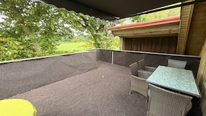 An outdoor patio area with a covered seating area, a table, and chairs. - Feldblick Rastede Vacation Rental – Covered Patio, Air Conditioning, Dogs Welcome (Rastede)