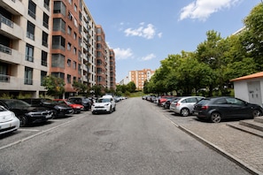 Ein Parkplatz mit mehreren Autos, einer Reihe von Wohnhäusern und einem klaren Himmel.