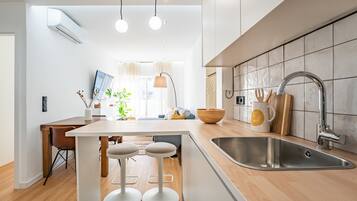Cocina moderna con una isla central, taburetes de bar, un fregadero y una zona de comedor con mesa y sillas.