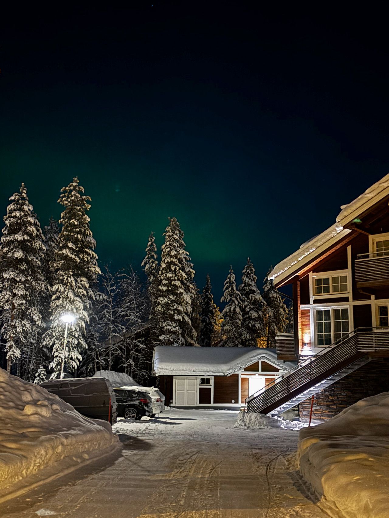 A snow-covered landscape with a building featuring a staircase and a garage.